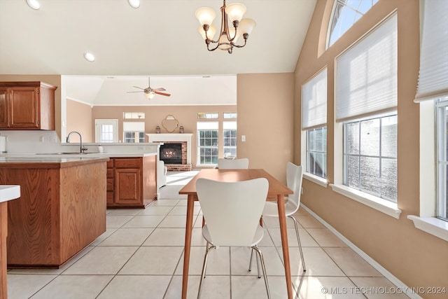 tiled dining area featuring ceiling fan with notable chandelier, vaulted ceiling, and sink