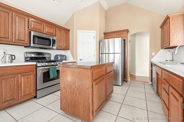 kitchen featuring light tile patterned flooring, appliances with stainless steel finishes, sink, and a kitchen island