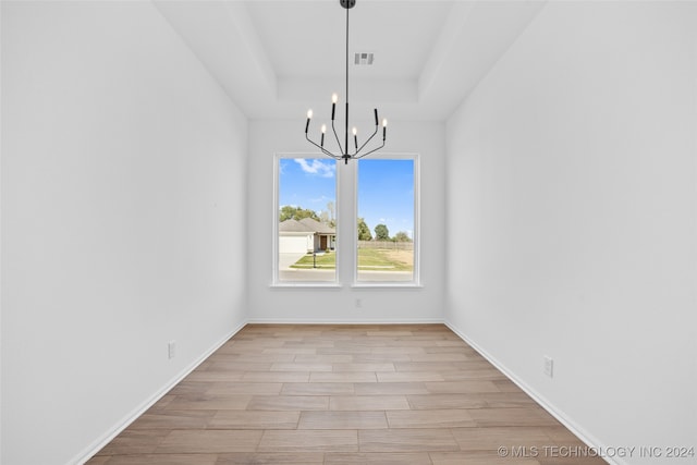 unfurnished dining area with an inviting chandelier and light wood-type flooring