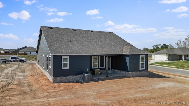 rear view of house featuring a garage and cooling unit