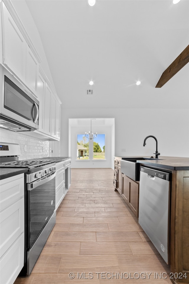 kitchen with backsplash, appliances with stainless steel finishes, white cabinetry, and light hardwood / wood-style floors