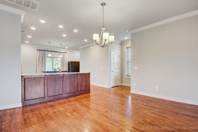 kitchen featuring light wood-type flooring, decorative light fixtures, and crown molding