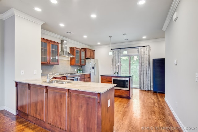 kitchen with sink, wall chimney exhaust hood, kitchen peninsula, and stainless steel appliances