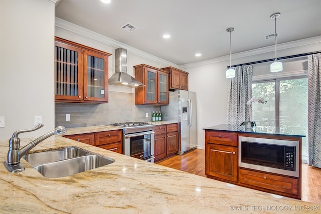 kitchen featuring sink, hanging light fixtures, wall chimney exhaust hood, light hardwood / wood-style flooring, and appliances with stainless steel finishes