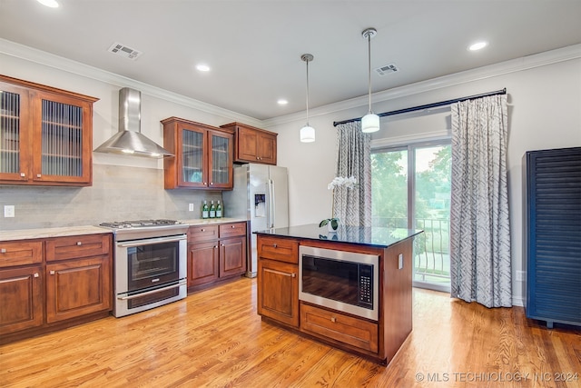 kitchen featuring a kitchen island, wall chimney exhaust hood, decorative backsplash, light hardwood / wood-style flooring, and appliances with stainless steel finishes