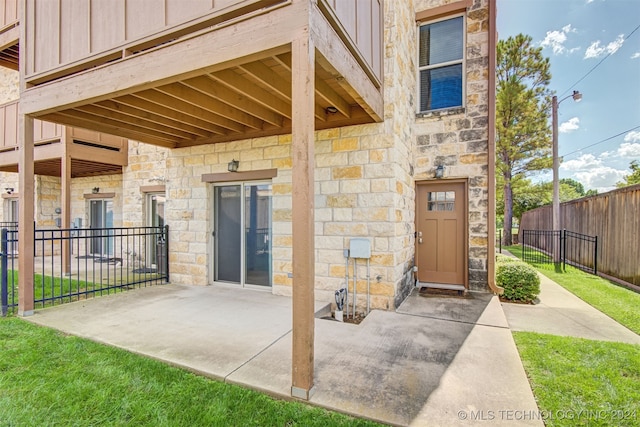 entrance to property featuring a patio and a yard