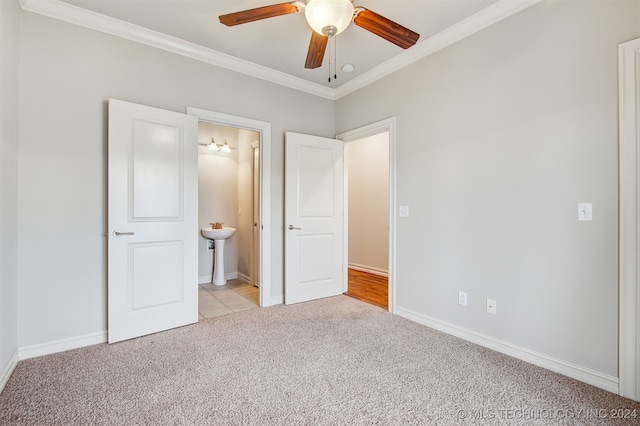 unfurnished bedroom featuring ornamental molding, ensuite bath, ceiling fan, and light colored carpet