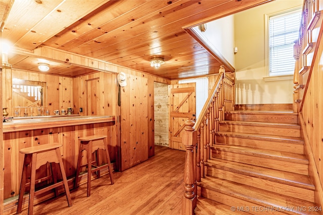 stairway featuring wooden walls, bar, hardwood / wood-style floors, and wooden ceiling