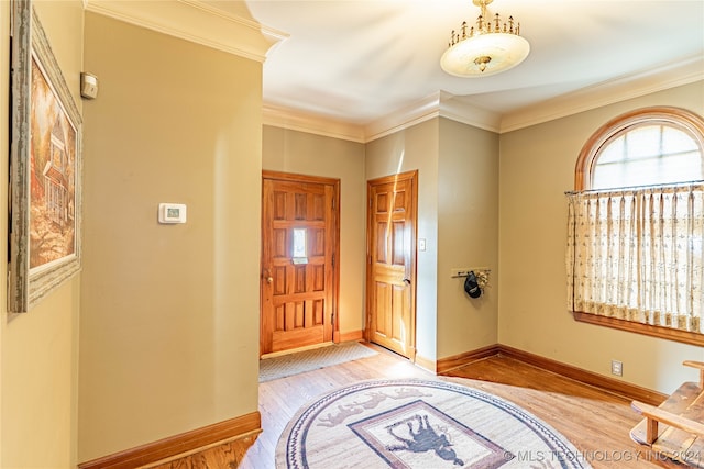 foyer entrance with light hardwood / wood-style floors and crown molding