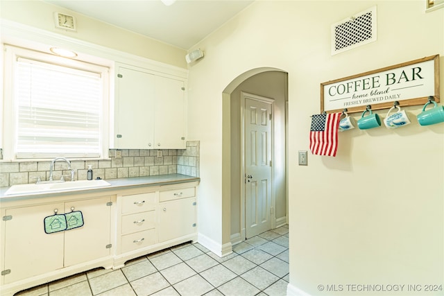 kitchen featuring light tile patterned floors, sink, decorative backsplash, and white cabinetry