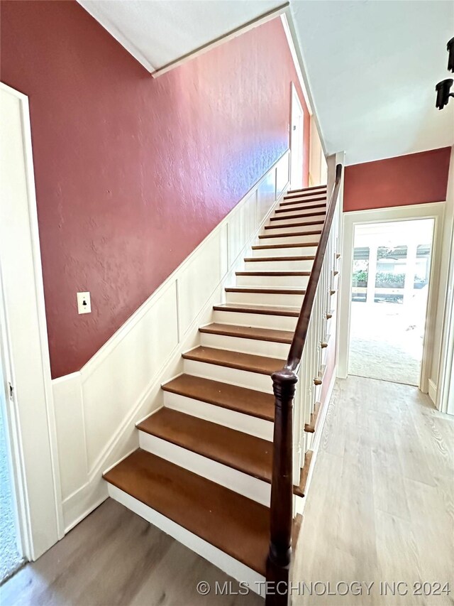 420 K St SW, Ardmore, OK 73401 - stairs with wood finished floors, a wainscoted wall, and a decorative wall