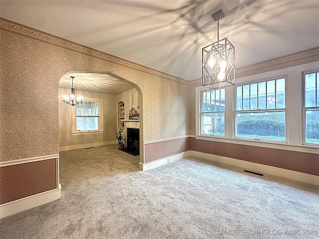 unfurnished dining area featuring carpet flooring, lofted ceiling, ornamental molding, and a chandelier