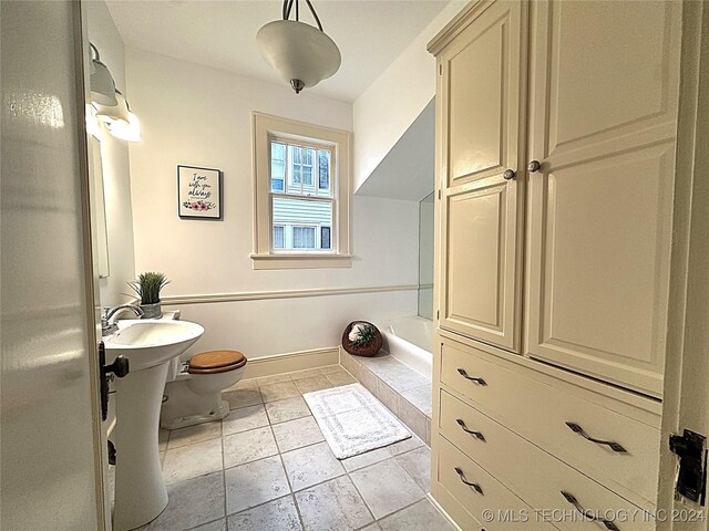 bathroom featuring tile patterned floors, toilet, and a bath