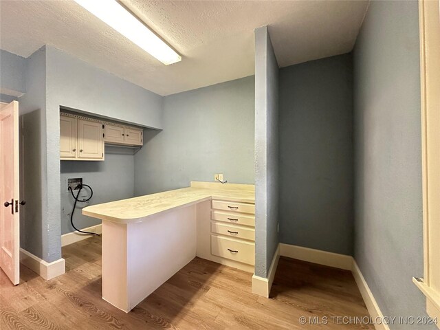 office area with light hardwood / wood-style floors and a textured ceiling