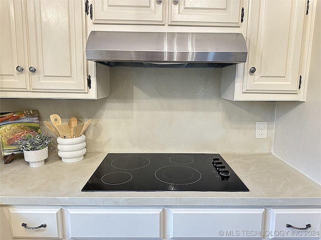 kitchen with white cabinetry, wall chimney range hood, and black electric cooktop