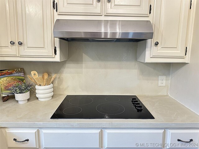 420 K St SW, Ardmore, OK 73401 - kitchen with wall chimney range hood, black electric cooktop, light countertops, and white cabinets