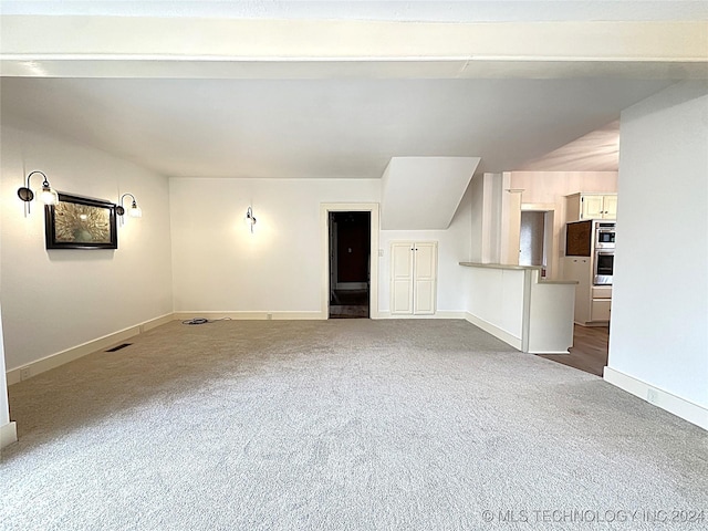 unfurnished living room with carpet flooring and vaulted ceiling