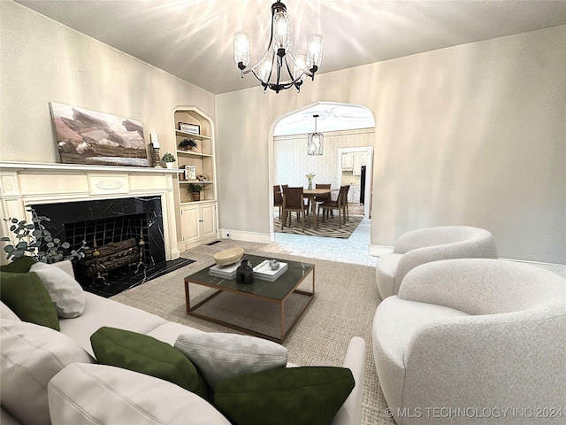 living room with a fireplace, built in features, carpet floors, and a notable chandelier