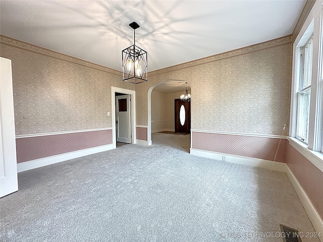 carpeted spare room featuring an inviting chandelier and crown molding