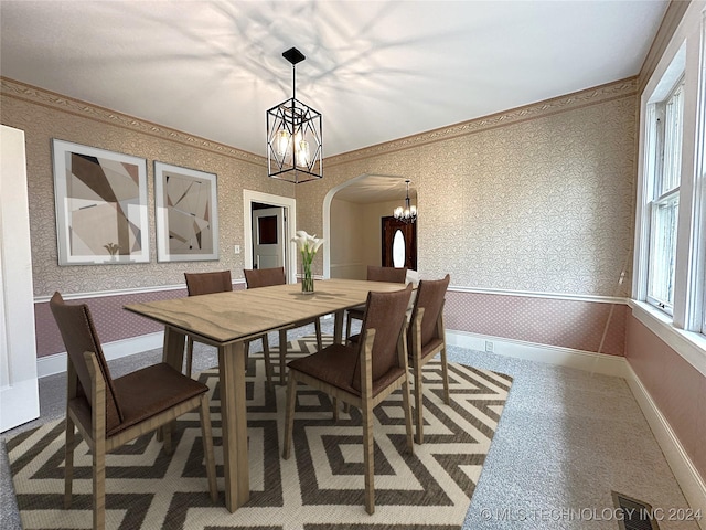 carpeted dining area featuring a chandelier and ornamental molding