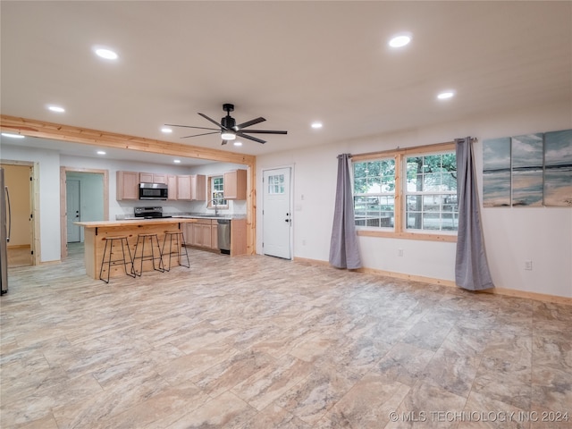 kitchen featuring a center island, a breakfast bar area, ceiling fan, and stainless steel appliances