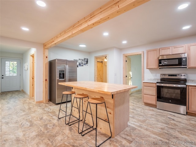 kitchen featuring a kitchen breakfast bar, stainless steel appliances, beam ceiling, light brown cabinetry, and wood counters