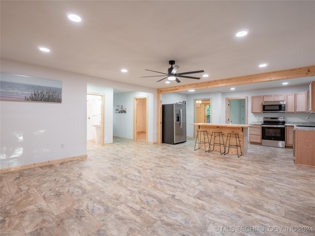 kitchen featuring a center island, sink, a breakfast bar area, stainless steel appliances, and ceiling fan