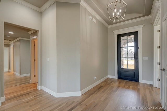 entrance foyer with ornamental molding, light hardwood / wood-style floors, and a notable chandelier