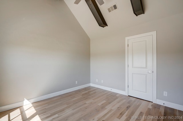 spare room featuring light wood-type flooring and high vaulted ceiling