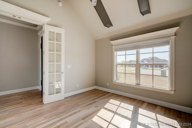 spare room featuring light wood-type flooring, vaulted ceiling, and french doors