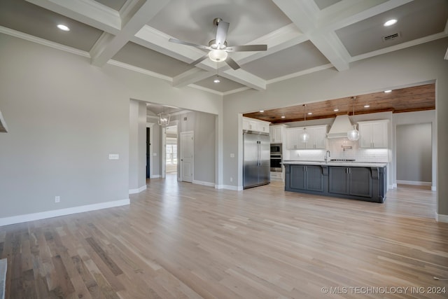 kitchen with tasteful backsplash, white cabinets, built in appliances, pendant lighting, and light hardwood / wood-style flooring