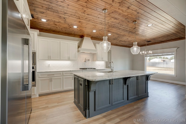 kitchen with white cabinets, custom exhaust hood, stainless steel appliances, and decorative light fixtures