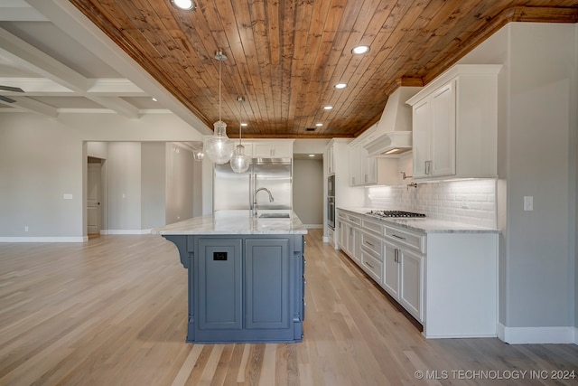 kitchen with light stone countertops, a center island with sink, light hardwood / wood-style floors, and white cabinetry