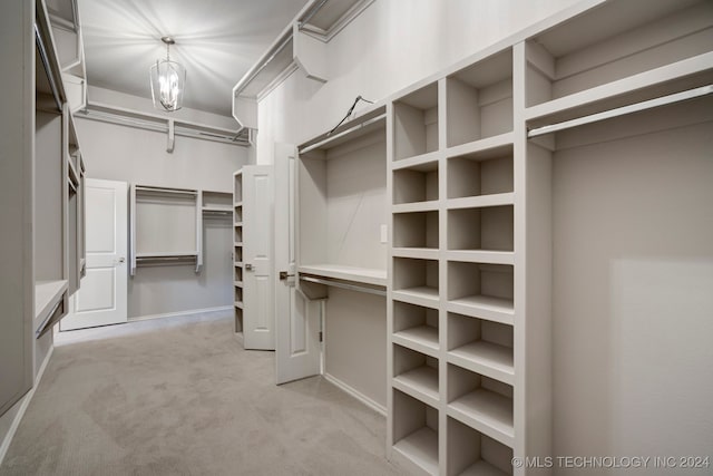 walk in closet with a chandelier and light colored carpet