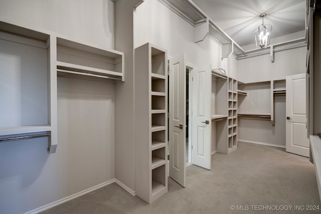 walk in closet with a chandelier and light colored carpet