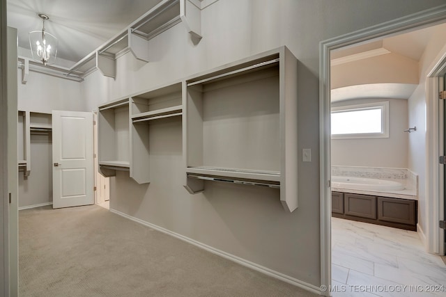 walk in closet featuring light carpet and a chandelier