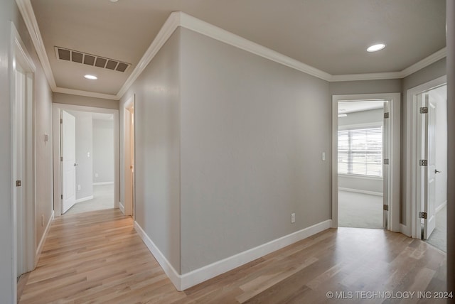 corridor with light wood-type flooring and ornamental molding