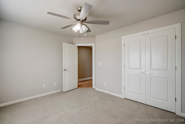 unfurnished bedroom featuring light carpet, a closet, and ceiling fan