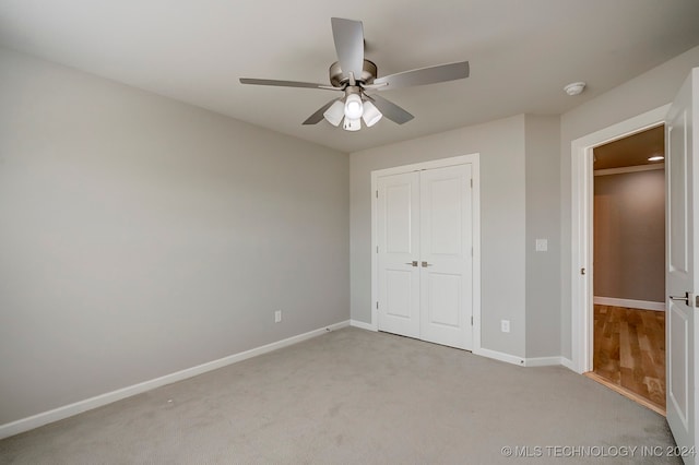 unfurnished bedroom featuring a closet, ceiling fan, and light colored carpet