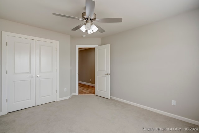 unfurnished bedroom with ceiling fan, light colored carpet, and a closet