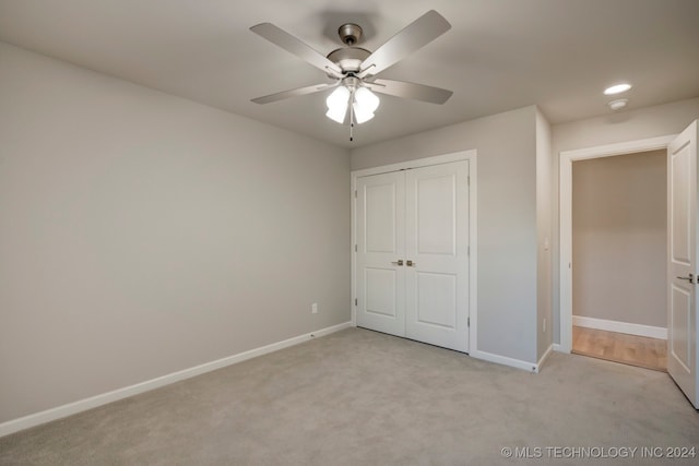 unfurnished bedroom featuring light carpet, a closet, and ceiling fan