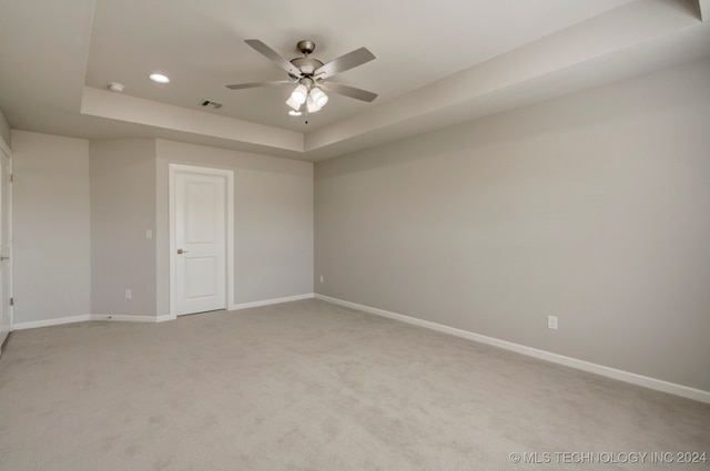 carpeted spare room with ceiling fan and a raised ceiling