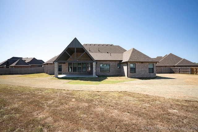 rear view of house featuring a lawn and a patio