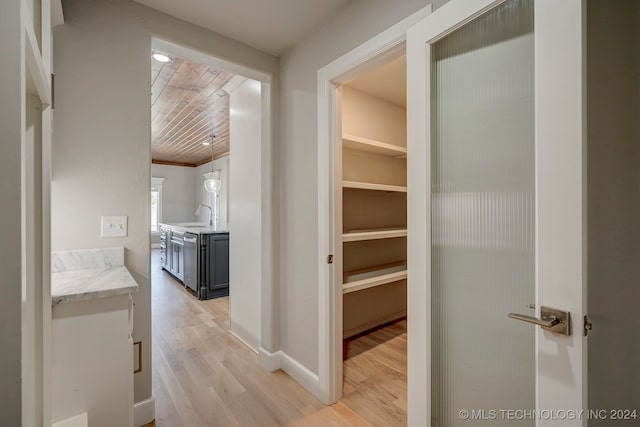 corridor featuring light hardwood / wood-style floors, wooden ceiling, and sink