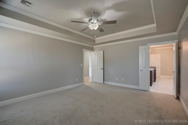 unfurnished bedroom featuring light carpet, a tray ceiling, ceiling fan, and ornamental molding