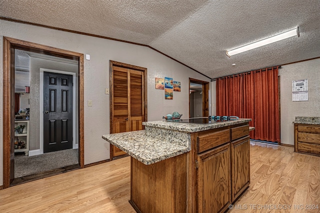 kitchen featuring a textured ceiling, lofted ceiling, light hardwood / wood-style floors, and a center island