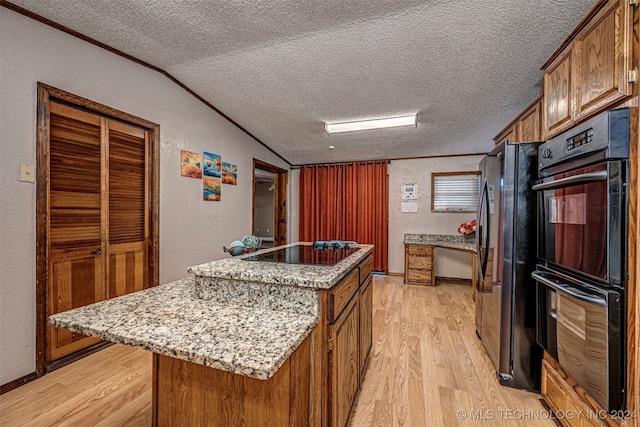 kitchen featuring black appliances, a textured ceiling, light wood-type flooring, and a center island