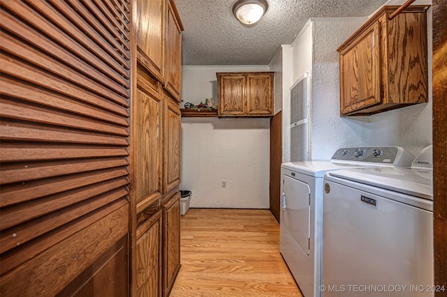 laundry room featuring washer and clothes dryer, cabinets, light hardwood / wood-style floors, and a textured ceiling