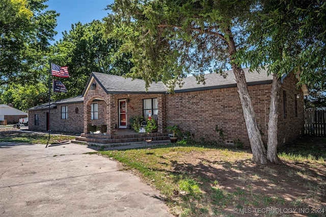 1202 N Pine St, Waurika, OK 73573 - view of front of property featuring roof with shingles, fence, and brick siding