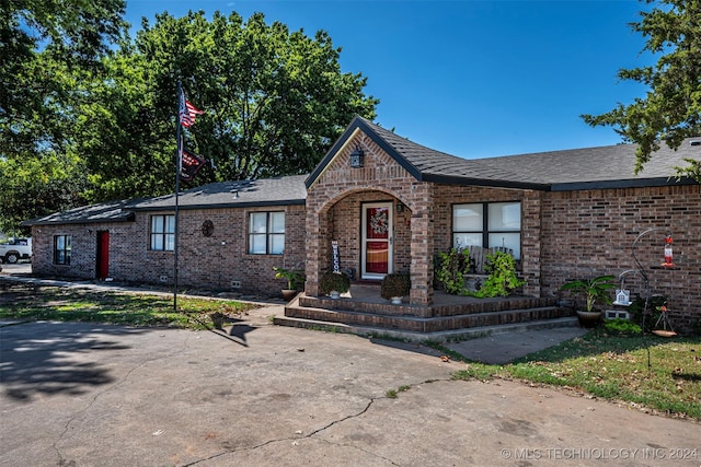 1202 N Pine St, Waurika, OK 73573 - view of front of home featuring roof with shingles, brick siding, and crawl space